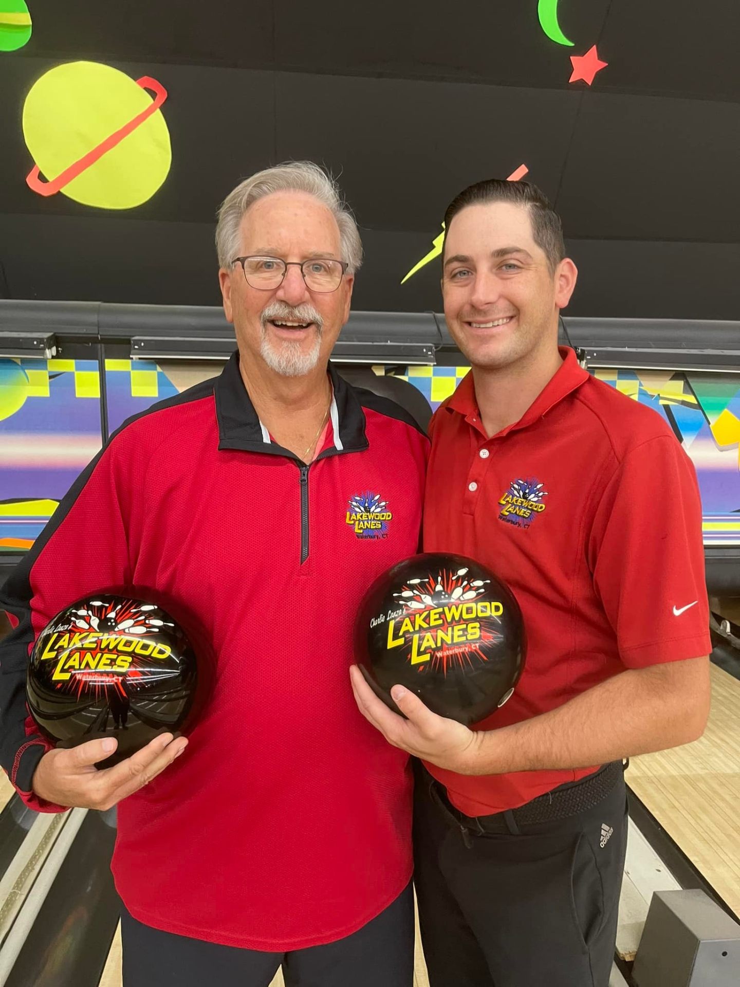 Staff members holding custom Lakewood Lanes bowling balls